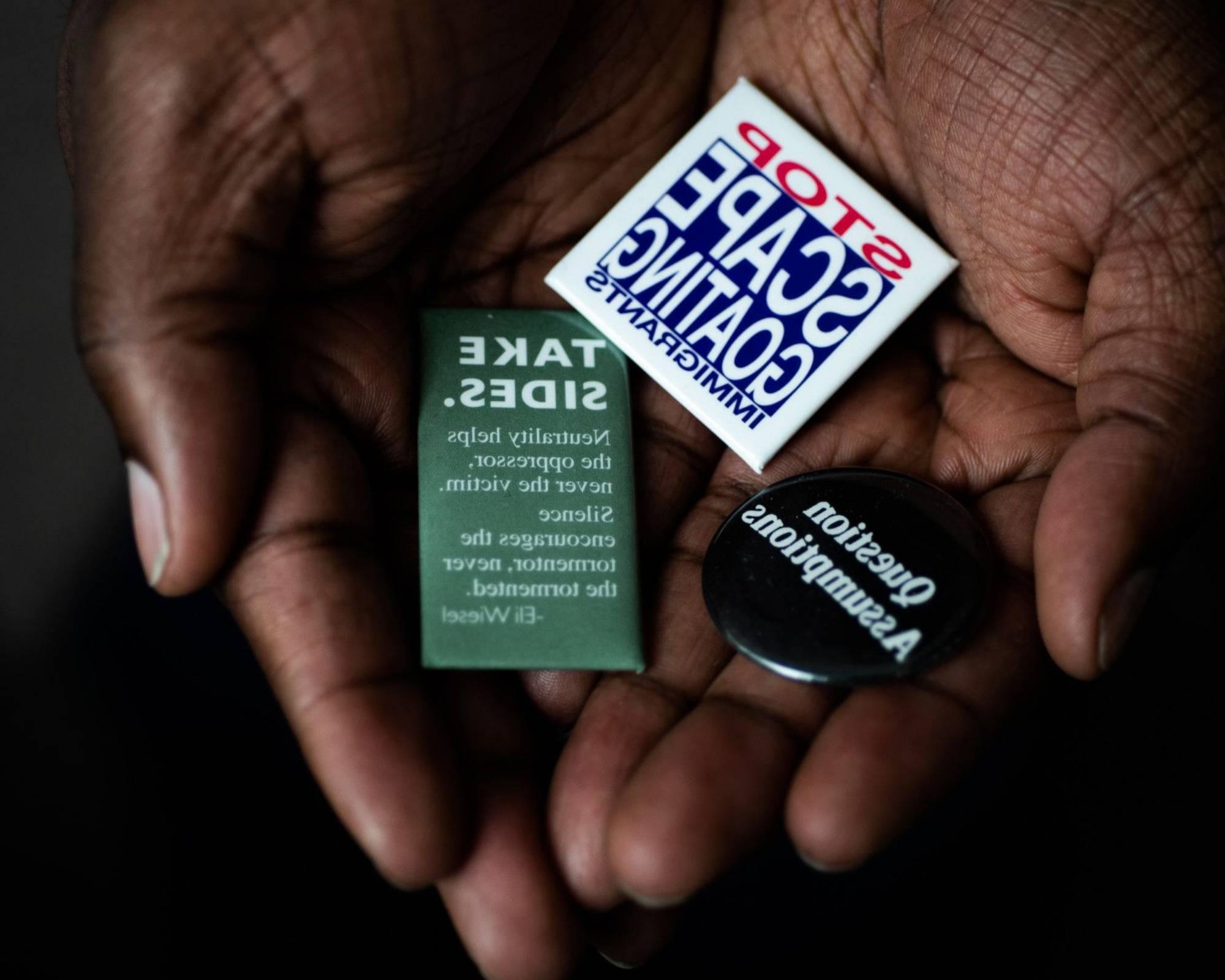 Cupped hands holding various social justice themed pins